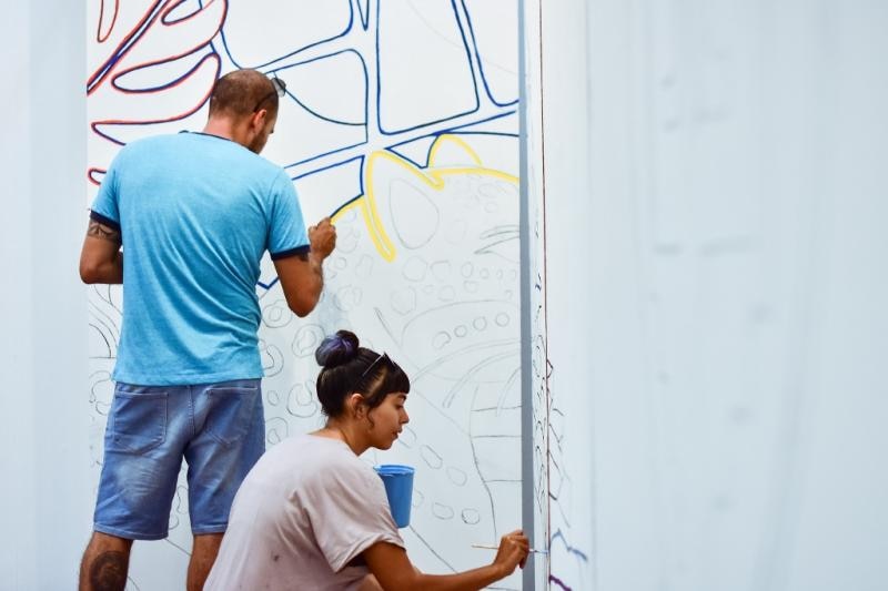 Dos artistas urbanos pintando un mural en la calle