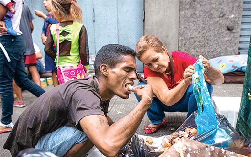 Un hombre rebusca en la basura para encontrar algo para comer