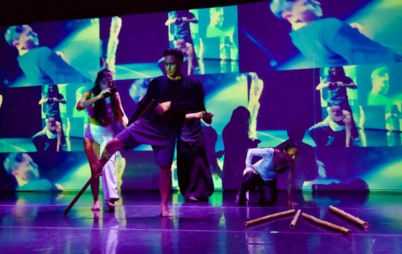 Jóvenes bailando en un escenario con proyecciones de video.