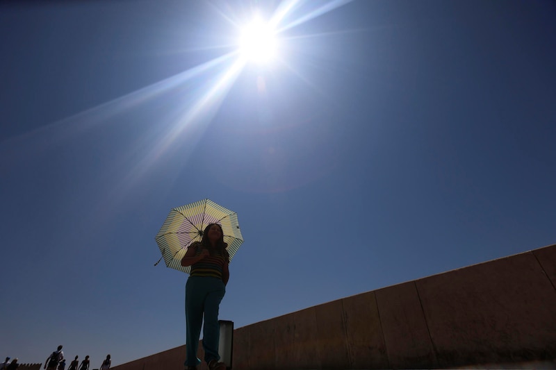 Mujer se protege del sol con una sombrilla