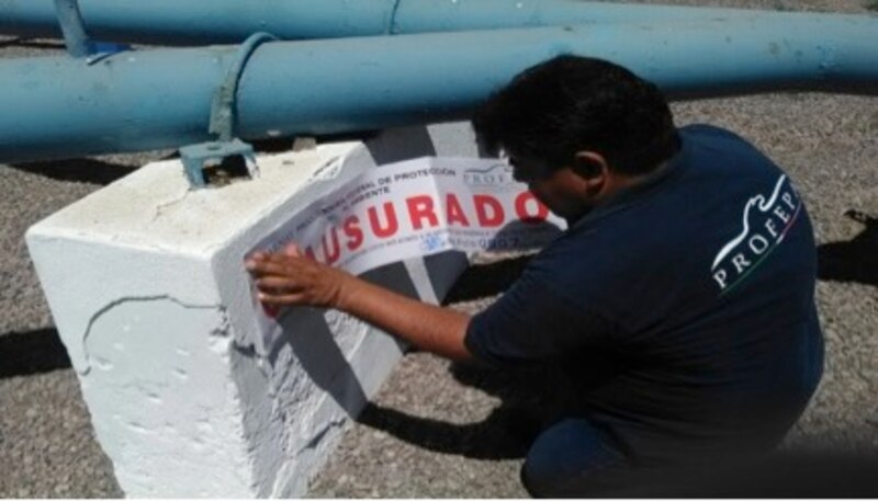 Un trabajador coloca una calcomanía de "Propiedad asegurada" en una tubería.