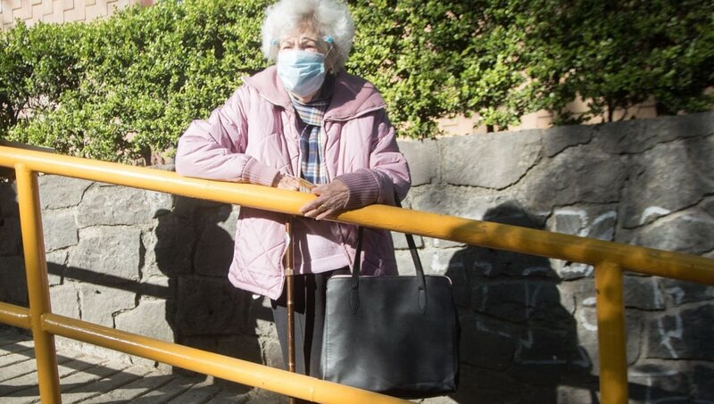Mujer mayor con bastón y mascarilla