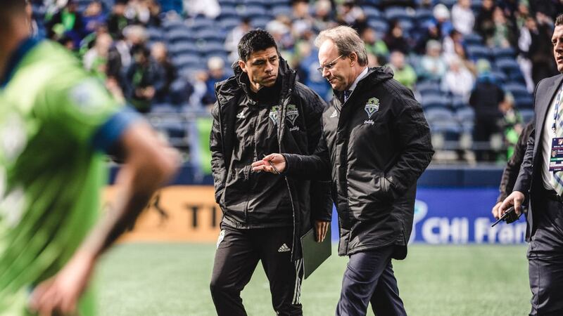 El entrenador del Seattle Sounders, Brian Schmetzer, habla con el director deportivo del club, Garth Lagerwey, durante un partido de la MLS.
