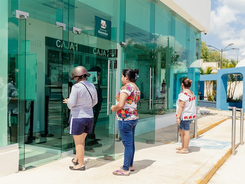 Joven consultando saldo en cajero automático del Banco del Bienestar con tarjeta de apoyo social