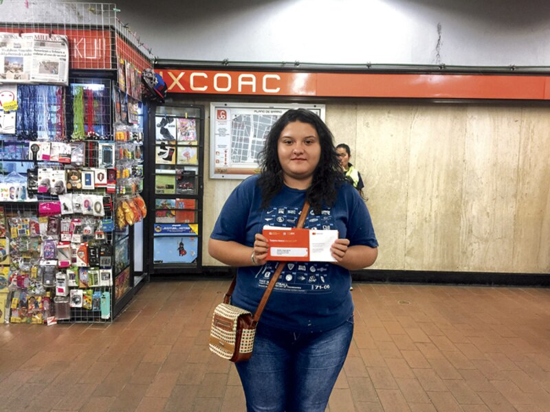 Mujer joven sostiene un boleto del metro en la estación Xoco