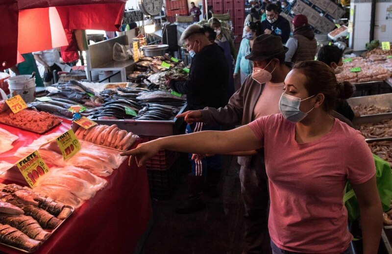 Mujer comprando pescado en un mercado mexicano
