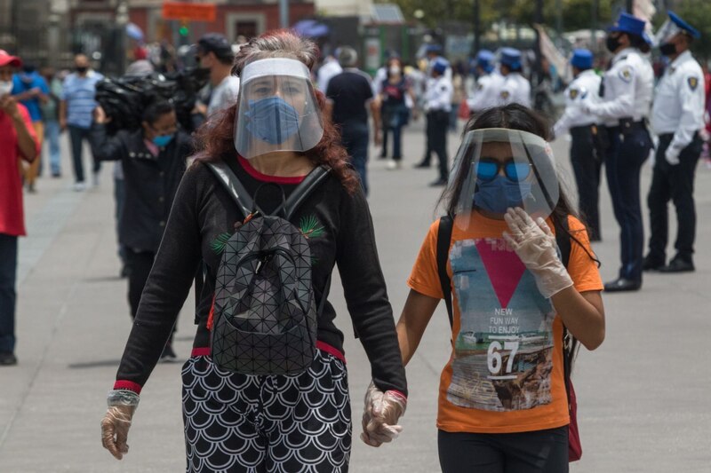 Madre e hija caminan por la calle con mascarillas