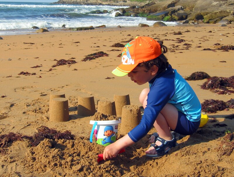 Niño construyendo un castillo de arena en la playa