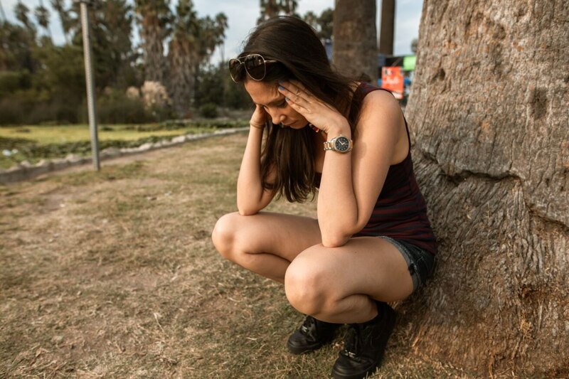 Mujer joven sentada en el suelo con la cabeza entre las manos