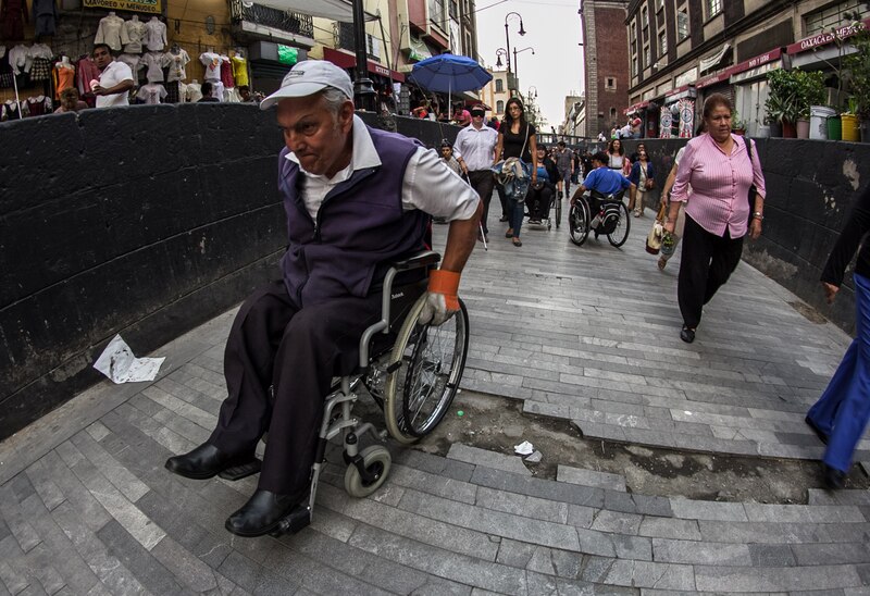 Un hombre en silla de ruedas se desplaza por una calle adoquinada en México