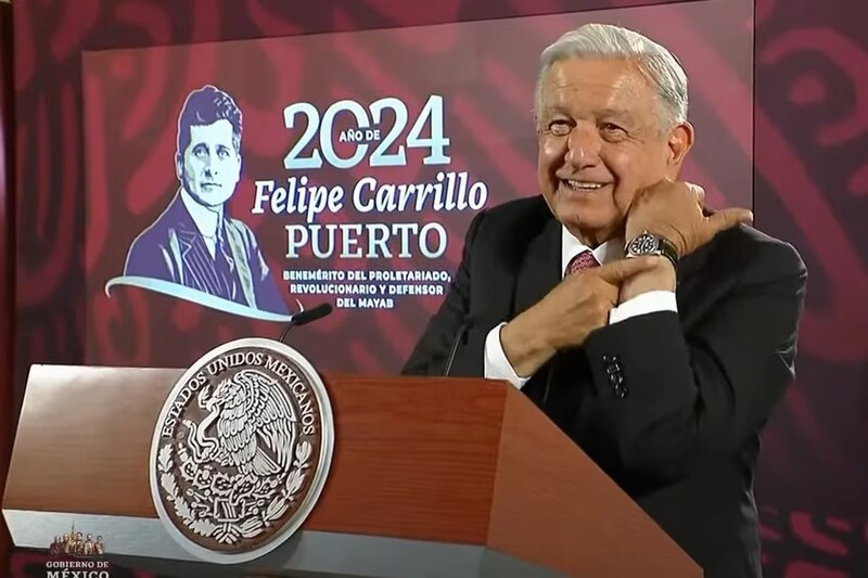 El presidente Andrés Manuel López Obrador muestra su reloj durante un discurso.