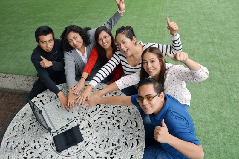 Un grupo de jóvenes profesionales trabajando juntos en una mesa al aire libre.
