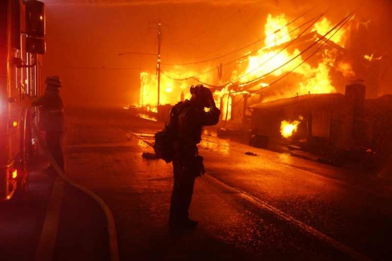 Un bombero reacciona mientras el incendio forestal de Palisades quema varias estructuras a lo largo de la Pacific Coast Highway en Malibú, California, EE.UU.