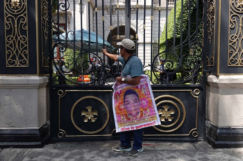 Un hombre sostiene un cartel con la foto de Christian Alfonso Rodríguez Telumbre, un joven desaparecido en Tixtla, Guerrero.