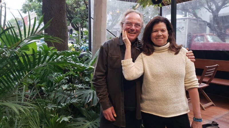 Pareja de mediana edad sonríe para una foto en un invernadero.