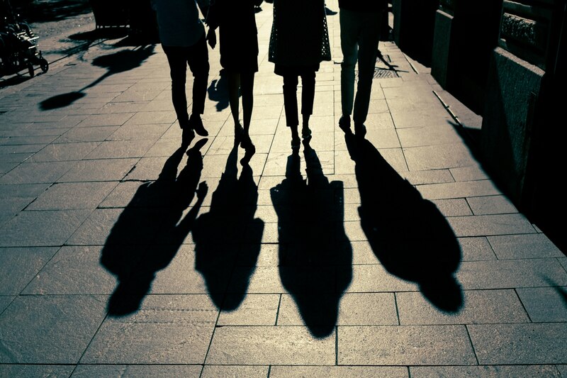 Imagen de cuatro personas caminando sobre la calle dejando una sombra