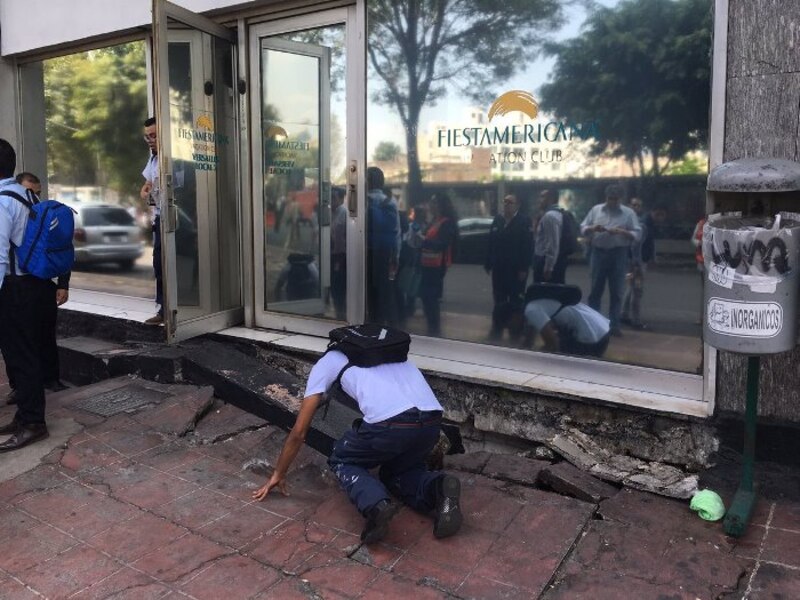 Un hombre revisa los daños en la calle después de un terremoto.