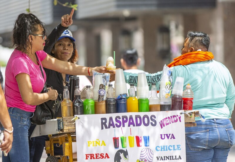 Mujer comprando raspados en un carrito de la calle