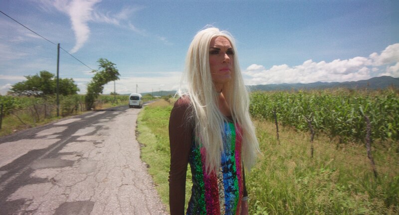 La mujer transgénero camina por una carretera rural.