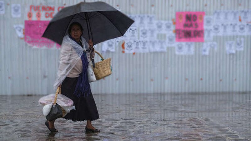 Mujer indígena camina bajo la lluvia en México