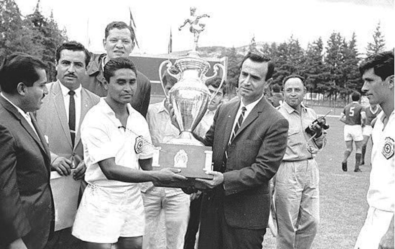 El futbolista peruano Teodoro Fernández recibe la copa del campeonato de manos del presidente de la FIFA, Stanley Rous, tras ganar la Copa América de 1957.