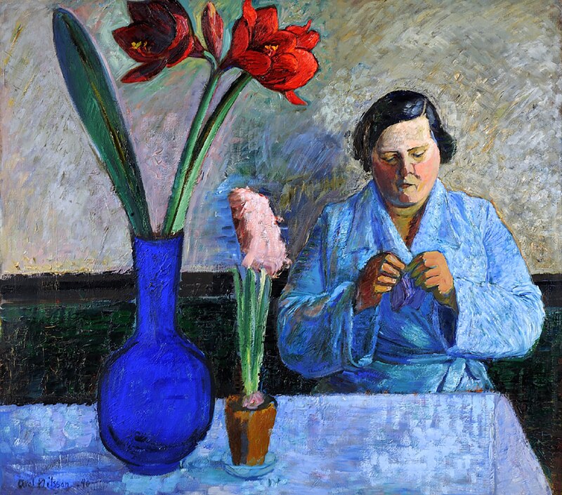 Mujer cosiendo junto a un jarrón con flores