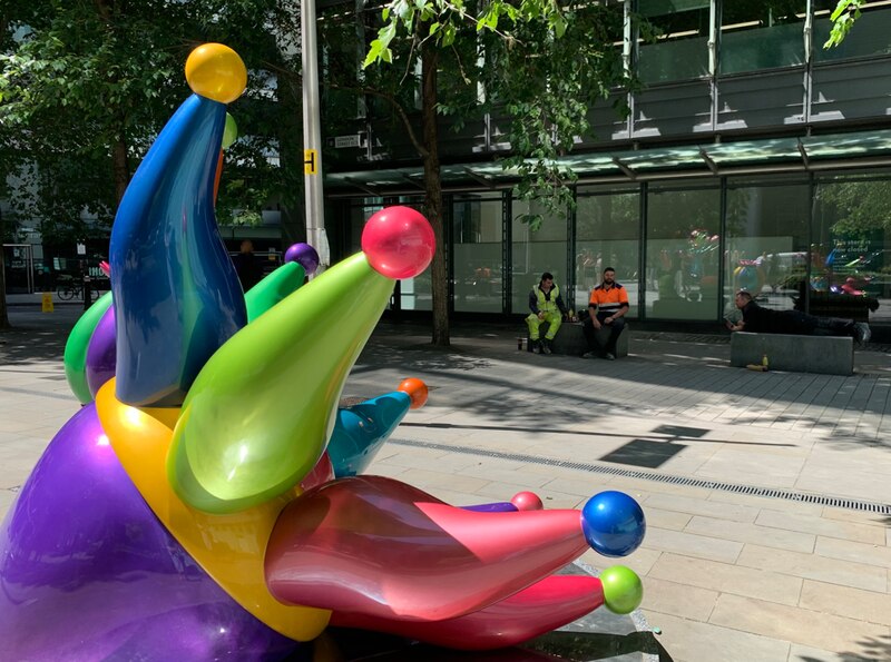 Escultura de un arlequín sentado en un banco