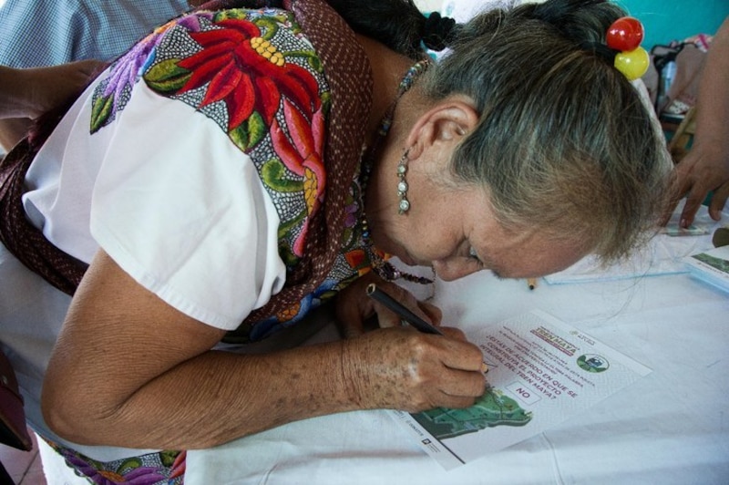 Mujer indígena firma un documento.