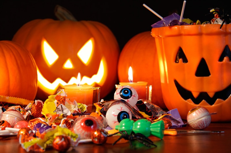 Una imagen de Halloween con calabazas, dulces y velas.