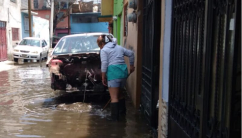 Mujer mexicana barre el agua de la inundación de su casa