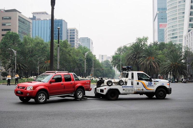 Grúa remolcando un coche rojo en la ciudad