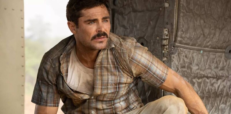 Un hombre con bigote y camisa a cuadros mira hacia la izquierda