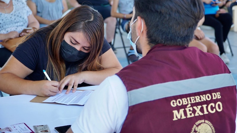 Mujer firma un documento mientras un hombre mira