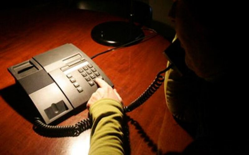 Mujer marcando un número de teléfono en un teléfono negro antiguo