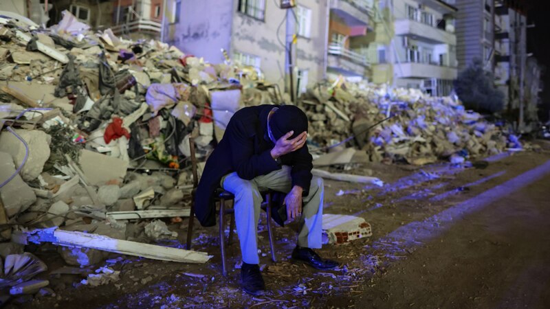 Un hombre sentado en una silla en medio de los escombros tras un terremoto.