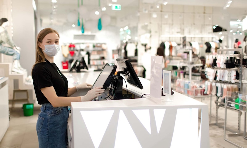 Cajera con mascarilla en una tienda de ropa
