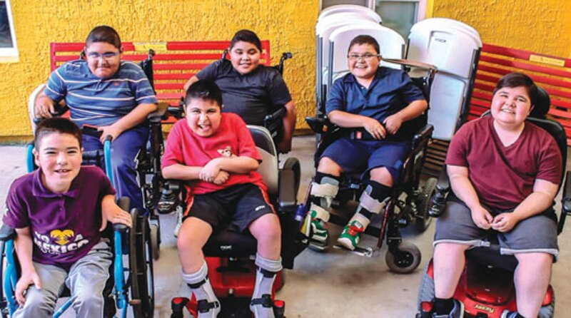 Niños en sillas de ruedas sonríen a la cámara.