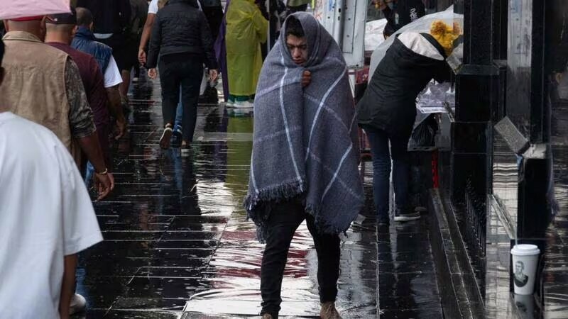 Un hombre camina por la calle mojada en una fría tarde de invierno.