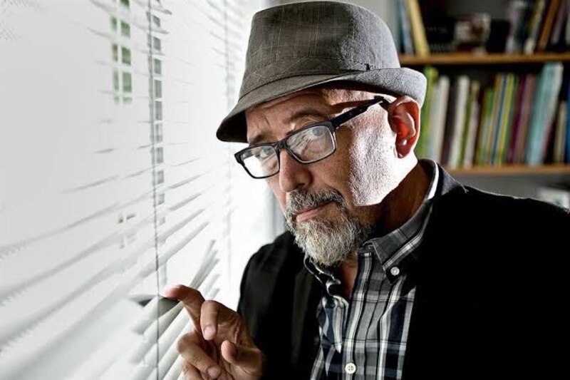 Un hombre mira a través de una persiana.