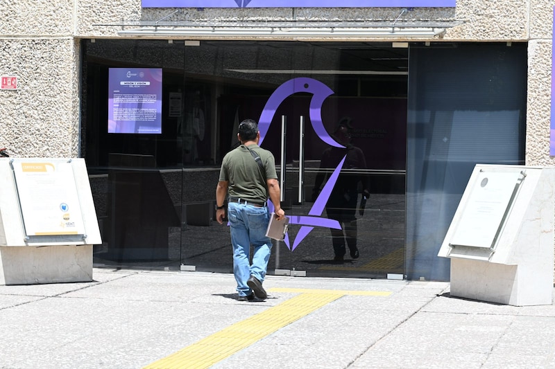 Un hombre camina frente a la puerta de cristal de un edificio