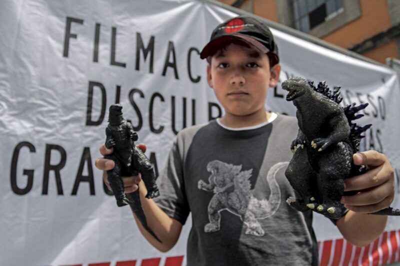 Niño sostiene dos figuras de Godzilla