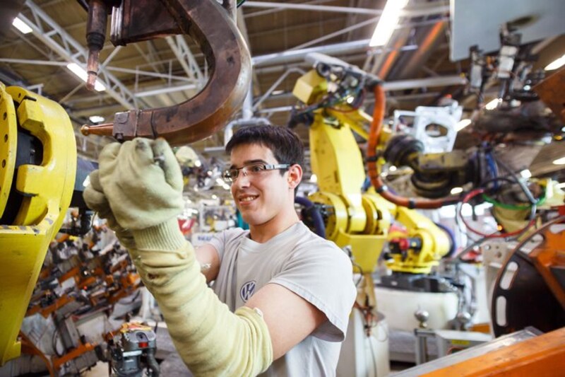 Un joven aprendiz de Volkswagen soldando una pieza de metal en una fábrica.