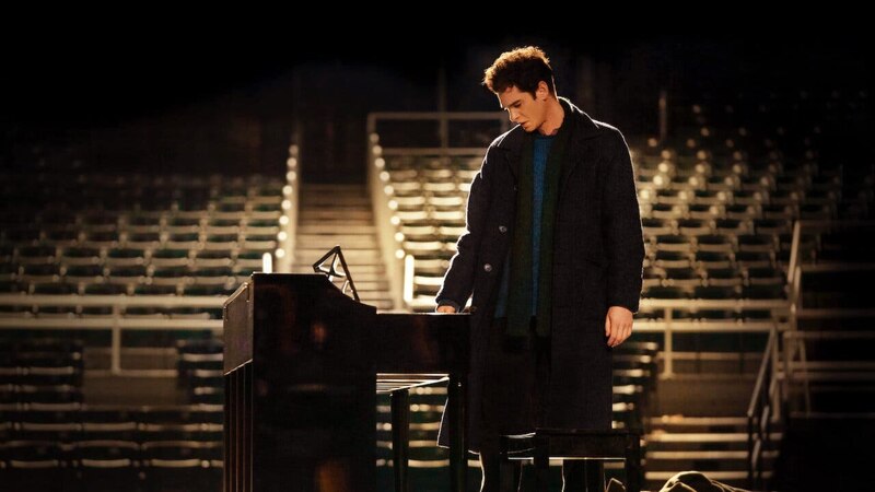 Un joven tocando el piano en un teatro vacío