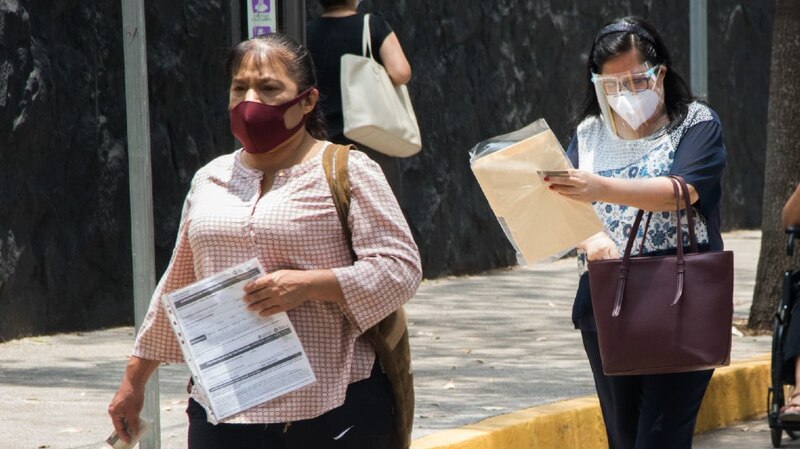 Mujeres caminan por la calle con mascarillas