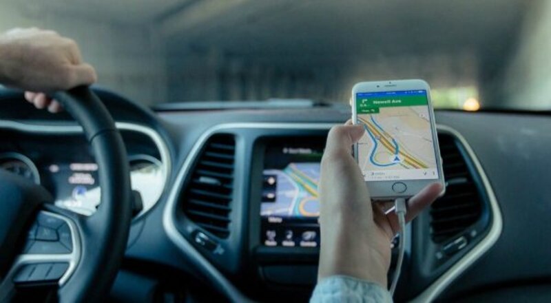 Mujer usando un teléfono inteligente como GPS mientras conduce