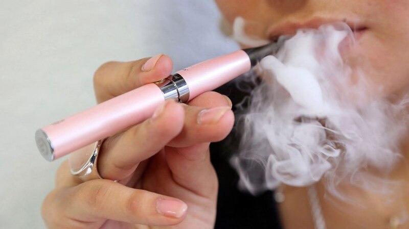 Mujer joven fumando un cigarrillo electrónico