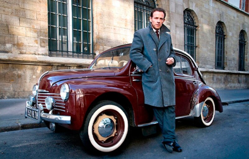 Un hombre elegante junto a un coche antiguo
