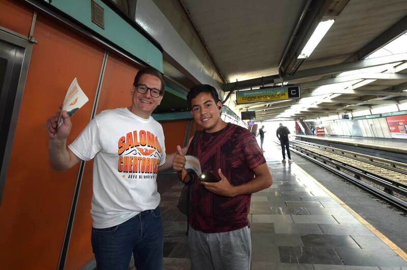 Un hombre y un joven sonríen y posan para una foto en una estación de metro.