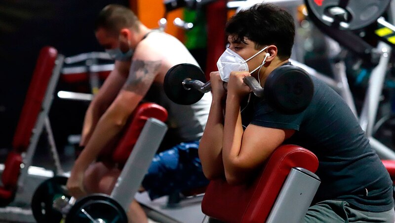 Joven haciendo ejercicio en el gimnasio con mascarilla