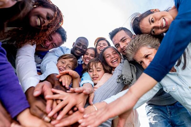 Un grupo de personas de diferentes razas y etnias se unen para formar un círculo y levantar sus manos en señal de unidad.